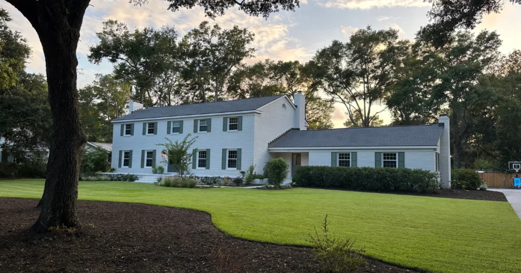 white brick charleston home with green exterior shutters